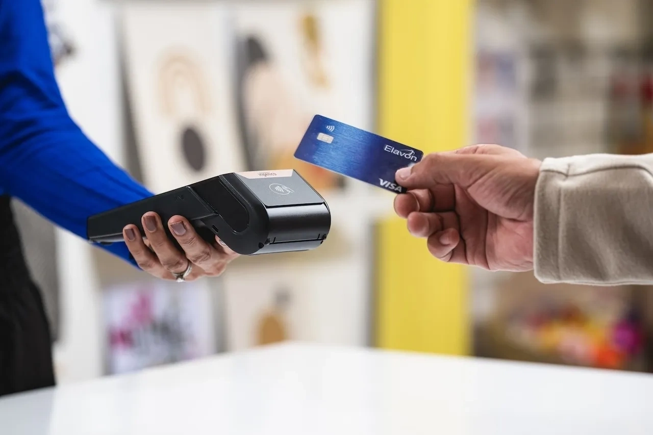 Close-up of a contactless card payment being made with a blue credit card and a wireless card reader.